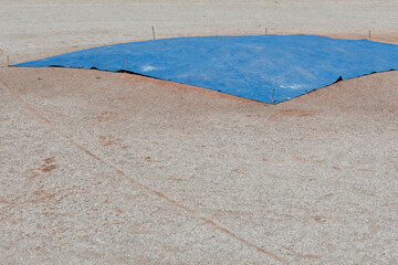blue tarp on a pitcher's mount at a baseball diamond
