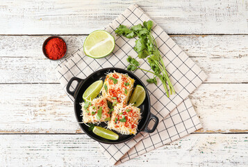Frying pan with tasty Elote Mexican Street Corn on white wooden background