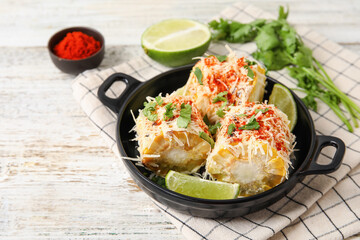 Frying pan with tasty Elote Mexican Street Corn on white wooden background