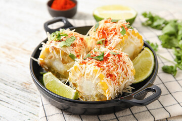 Frying pan with tasty Elote Mexican Street Corn on white wooden background