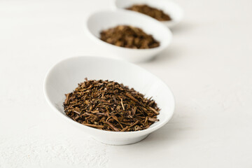 Bowls of dry hojicha green tea on light background