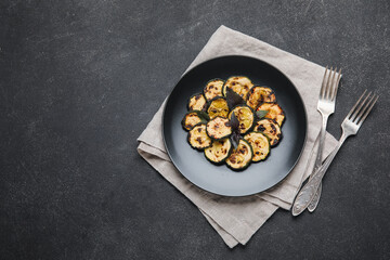 Plate with tasty grilled zucchini on dark background