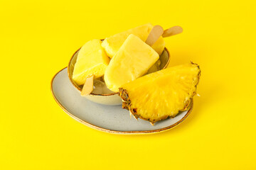 Plate with tasty pineapple popsicles on color background