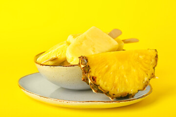 Plate with tasty pineapple popsicles on color background