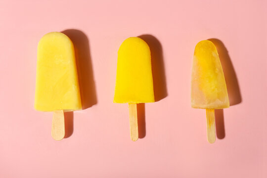 Tasty pineapple popsicles on color background