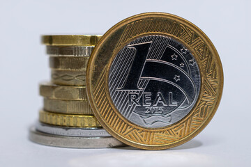 Close up of 1 real Brazilian coin and stack of various coins