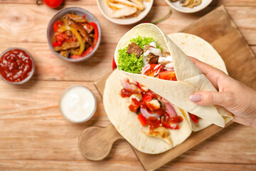 Woman with tasty Fajitas on wooden background