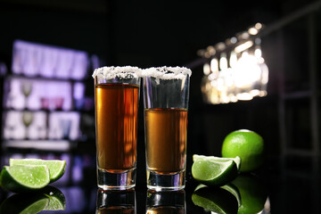 Shots of tasty tequila with lime on table in bar