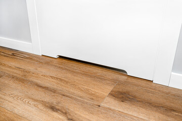 Close up shot of a white door with a vent in a modern home with vinyl planks on the floor.