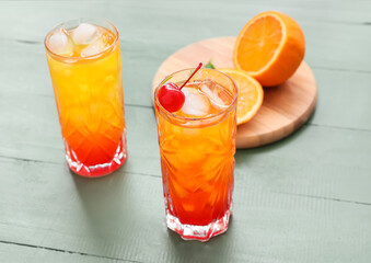 Glass of tasty Tequila Sunrise cocktail on color wooden background