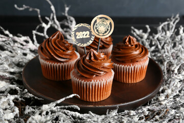 Plate with tasty cupcakes for New Year 2022 celebration on table