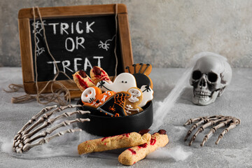 Bowl with tasty cookies for Halloween celebration on grunge background