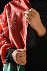 Woman with flag of Afghanistan on dark background, closeup