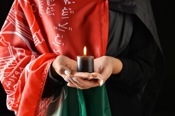Woman with flag of Afghanistan and candle on dark background, closeup