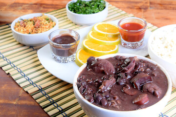 delicious Brazilian food feijoada with beans, pork, bacon, sausage with cabbage, rice, salad, spices and pepper. rustic cuisine.