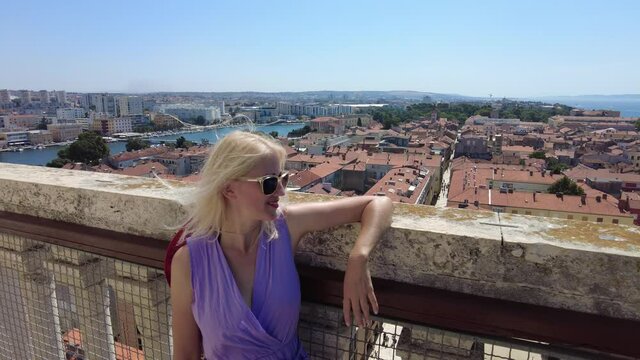 Woman with hat on top view of Zadar city of Croatia on Adriatic Sea and capital of Dalmatia. Panoramic terrace of Cathedral bell tower Katedrala Sv. Stosije. Aerial view of the cityscape in summer.