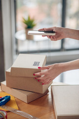 Female with red nails holding her smartphone over a cardboard box