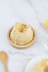 Homemade lemon cake classic recipe, decorated with sugar icing on marble table. Healthy organic summer dessert pie with yellow tulip on background. 