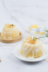 Homemade lemon cake classic recipe, decorated with sugar icing on marble table. Healthy organic summer dessert pie with yellow tulip on background. 