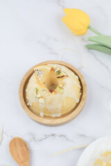 Homemade lemon cake classic recipe, decorated with sugar icing on marble table. Healthy organic summer dessert pie with yellow tulip on background. 