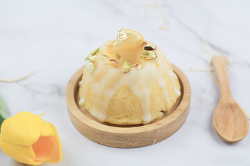 Homemade lemon cake classic recipe, decorated with sugar icing on marble table. Healthy organic summer dessert pie with yellow tulip on background. 