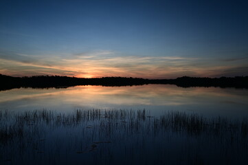 Fototapeta premium Colorful sunrise cloudscape reflected in calm water of Nine Mile Pond in Everglades National Park, Florida in summer.