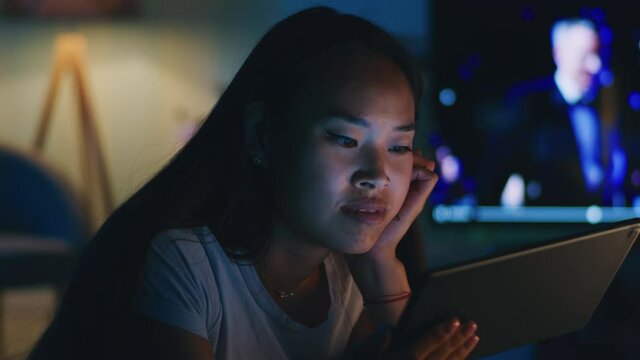 Asian female watching video on tablet in evening