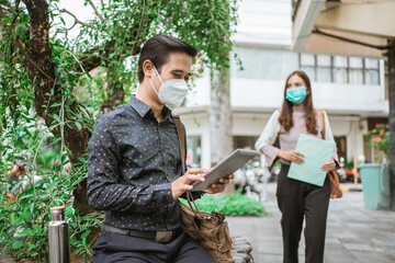 two busy worker sitting in the park during office break using phone