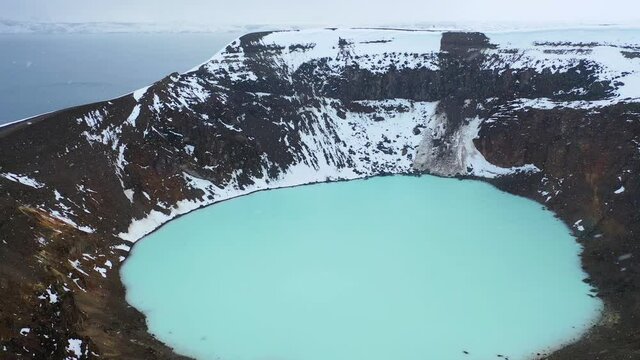 Aerial drone shot flying outdoors above the forest lake during winter. Adventure journey in beautiful landscape in Askja Lake, the crater of Askja Volcano Iceland with calmness water flowing and snow.