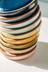 A large stack of ceramic cups in pastel colors.