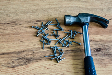 Metal hammer with nails on a wooden table. Close up. Carpenter concept