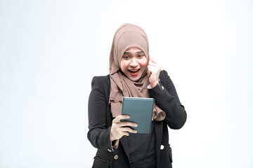 An office worker for an Asian Muslim woman stands and is very happy to see the work at the table computer screen, on white background.