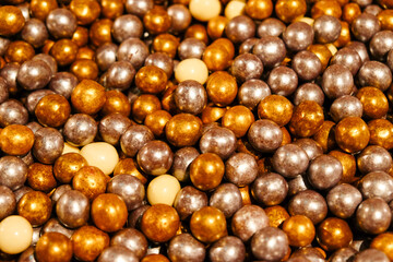 Colorful candies, selective focus. Gold, silver, chocolate and white candies, heap of candies for background