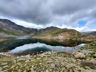 Summit Lake on Mount Evans, Colorado under dramatic summer cloudscape reflected in still water of lake..