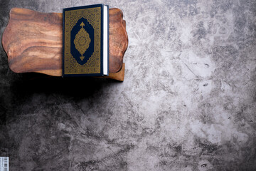 Islamic concept - The Holy Al Quran with written Arabic calligraphy meaning of Al Quran, on wooden stand, with copy space.