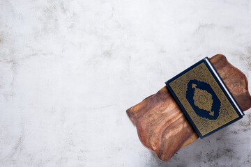 Islamic concept - The Holy Al Quran with written Arabic calligraphy meaning of Al Quran, on wooden stand, with copy space.