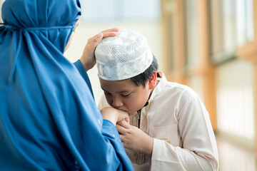 Concept Eid Mubarak, Picture of a Muslim boy in Islam following his mother with love at the mosque after prayer.