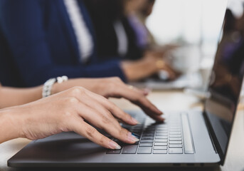 Selective focus on business woman's hands sitting and working on laptop on conference table in office. Concept for business meeting