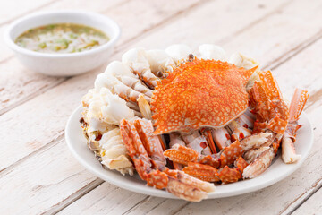 steamed crabs with spicy dipping sauce in white ceramic plate on white old wood texture background, blue swimming crab, flower crab, blue crab © flukesamed