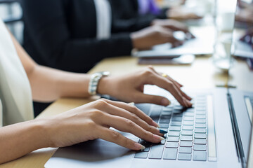 Selective focus on business woman's hands sitting and working on laptop on conference table in office. Concept for business meeting