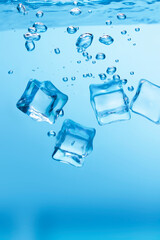 Ice cubes in blue water create bubbles that float to the surface, blue liquid.