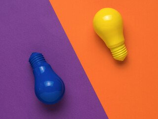 Blue and yellow light bulbs on an orange and purple background. Minimalism. Flat lay.