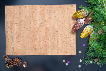 Layout on the theme of the New Year 2022 with a parchment sheet, toys and branches of a Christmas tree on a dark background.