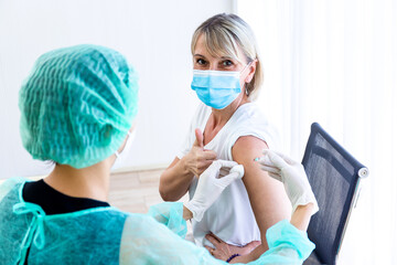 Women wearing masks getting vaccinated. Concept of coronavirus, vaccination elderly woman mask who approved covid-19 vaccination at hospital. Female doctor immunizes elderly patients against the virus