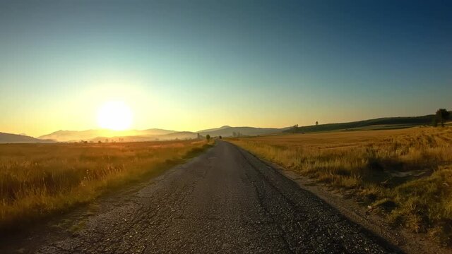 Summer sunrise, car drive on local narrow craggy road, beautiful lowland driver perspective