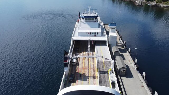 Car ferry Mf Oppedal loading cars in the port of Lavik in sogn norway - Static aerial over deck looking down at crewmwmber and cars driving onboard - Norled company