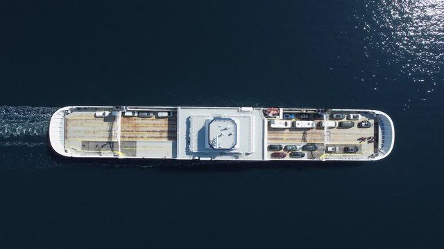 Top-down birdseye view of ferry Oppedal from Norled company transporting cars across the Sognefjord along European road E39 at a sunny summer day - Aerial following ship form above
