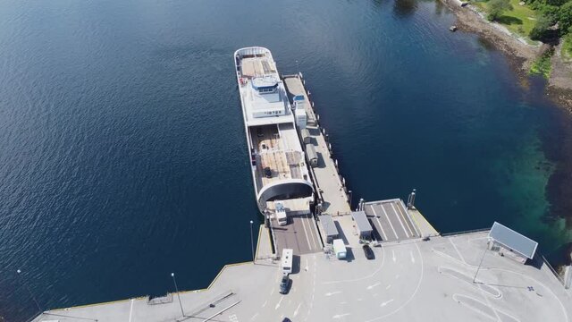 Unloading ferry Oppedal to road E-39 at Lavik ferry pier in Norway - Beautiful bacwards moving aerial showing ferry before revealing harbour with ferry queue and road - Norway