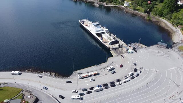 Car and passenger ferry Mf Oppdeal loading and discharging cars to road E39 at Lavik harbour - Static aerial showing ferry with port and ferry queue - Norway