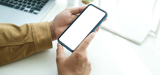 Close up view businessman sitting at his workspace and using smart phone.